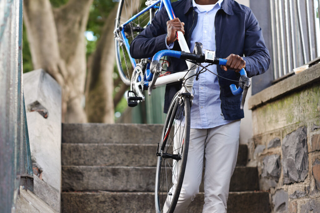 A man carries a bike down a flight of outdoor stairs
